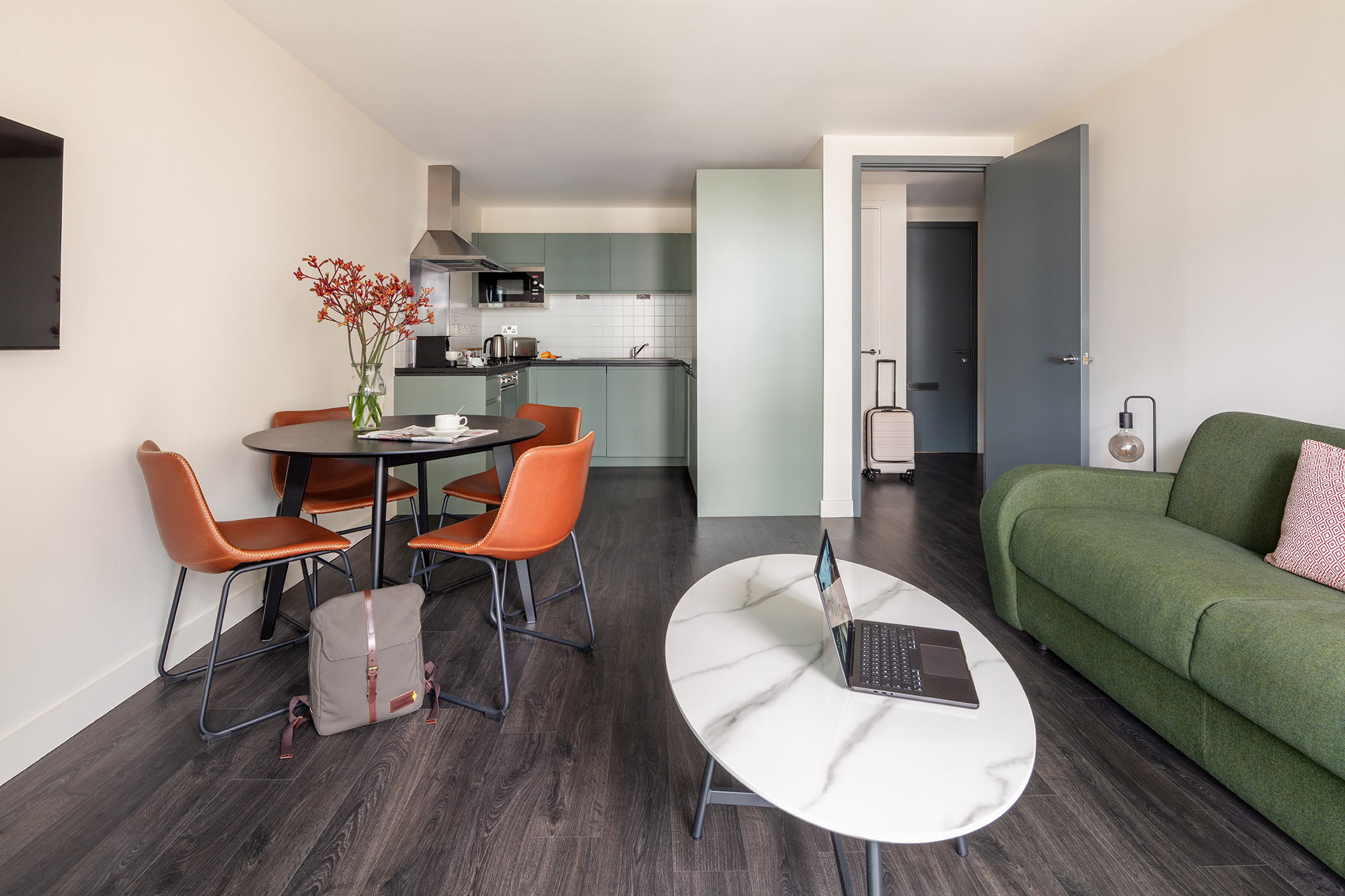 Marlin Canary Wharf photo of the living and kitchen area in a Two Bedroom Apartment. In the living area there is a green double sofa with a coffee table, side t